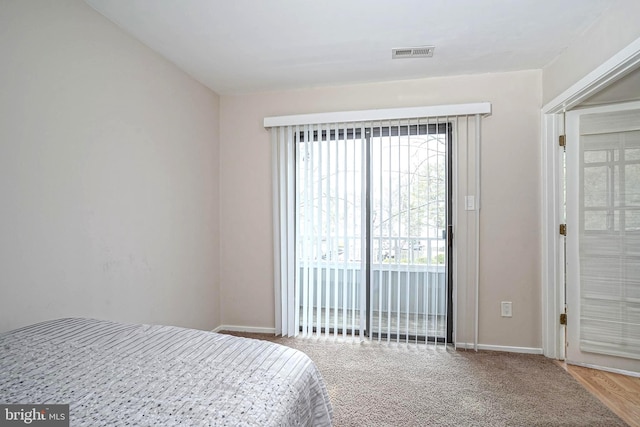 carpeted bedroom with visible vents, baseboards, and access to outside