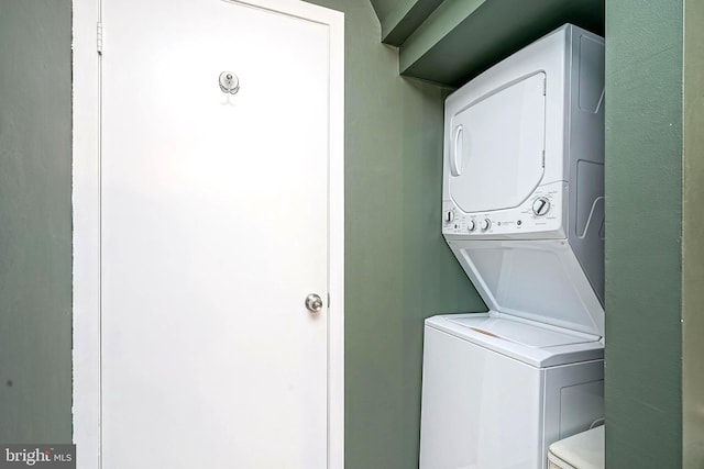 washroom with stacked washer and clothes dryer and laundry area