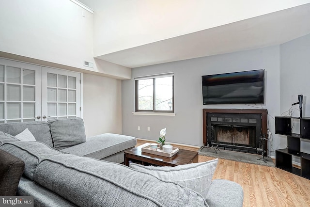 living area featuring visible vents, a fireplace with flush hearth, and wood finished floors