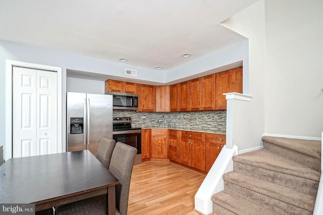 kitchen featuring visible vents, backsplash, brown cabinets, appliances with stainless steel finishes, and light wood-style floors