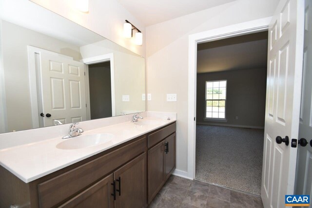 full bath featuring double vanity, baseboards, and a sink