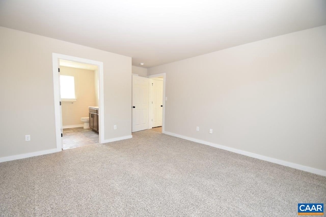 unfurnished bedroom featuring light carpet, connected bathroom, and baseboards