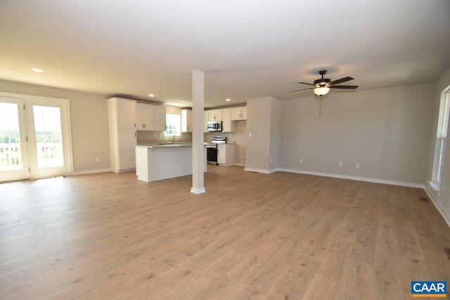 unfurnished living room with recessed lighting, light wood-type flooring, baseboards, and a ceiling fan