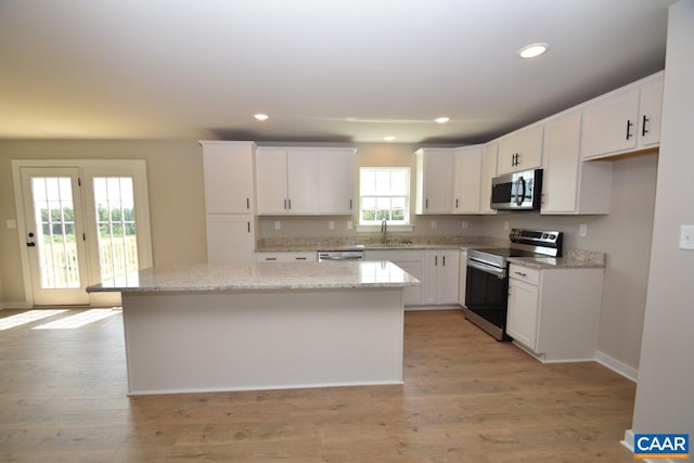 kitchen with recessed lighting, a sink, appliances with stainless steel finishes, white cabinetry, and a center island