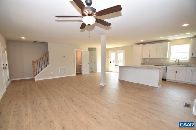 unfurnished living room with light wood finished floors, visible vents, stairs, and a sink