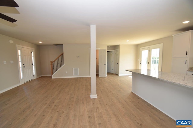 unfurnished living room featuring visible vents, recessed lighting, light wood-style floors, baseboards, and stairs