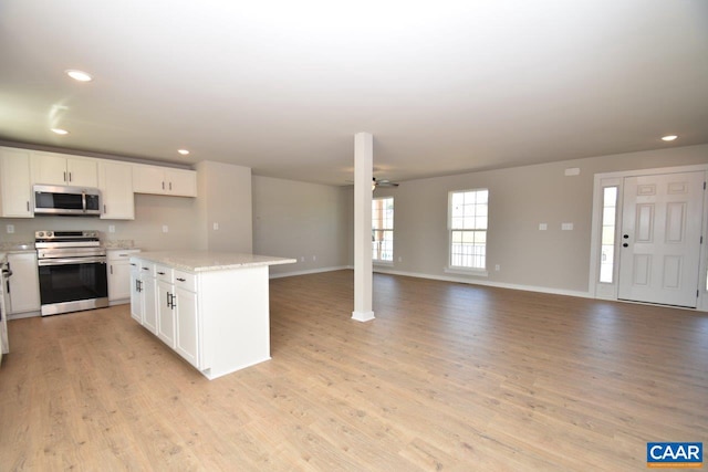 kitchen featuring light wood-style flooring, open floor plan, stainless steel appliances, white cabinets, and ceiling fan