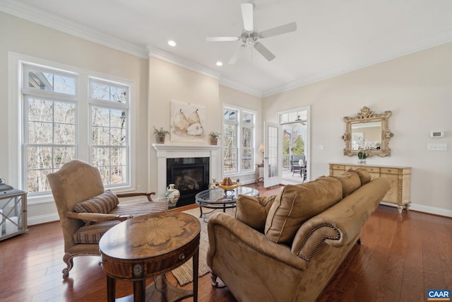 living room with baseboards, dark wood-type flooring, ceiling fan, and crown molding