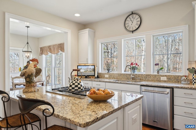 kitchen with a sink, light stone countertops, a breakfast bar area, white cabinetry, and stainless steel dishwasher