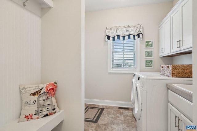 laundry area featuring washer and dryer, visible vents, cabinet space, and baseboards