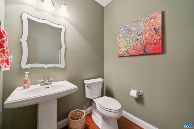 bathroom with baseboards, toilet, and wood finished floors