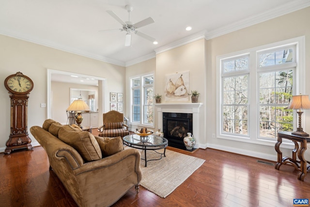 living area featuring visible vents, a healthy amount of sunlight, crown molding, and hardwood / wood-style flooring