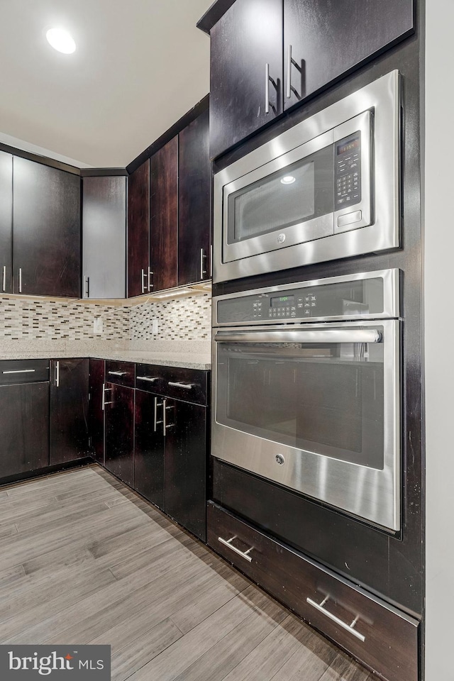 kitchen featuring light wood-style flooring, dark brown cabinets, backsplash, and stainless steel appliances