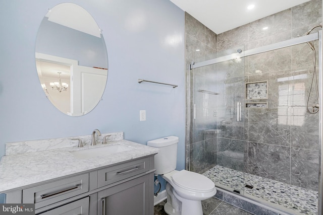 bathroom featuring tile patterned flooring, a shower stall, a chandelier, toilet, and vanity