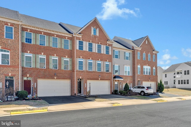 townhome / multi-family property with a garage, brick siding, and driveway