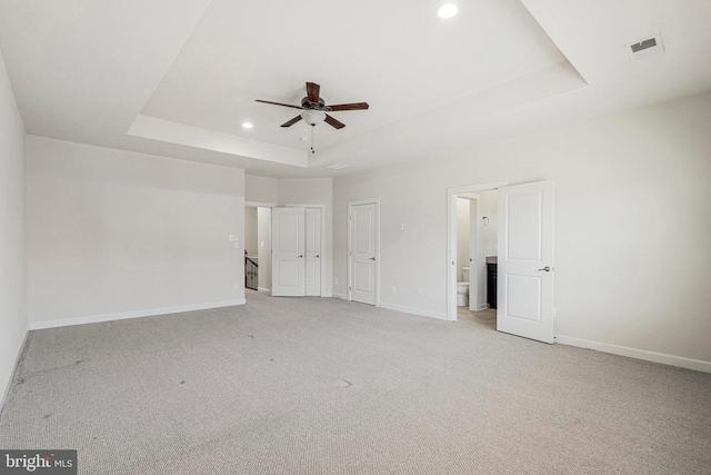 unfurnished bedroom featuring visible vents, baseboards, light carpet, recessed lighting, and a raised ceiling