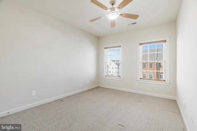 carpeted empty room with visible vents, ceiling fan, and baseboards