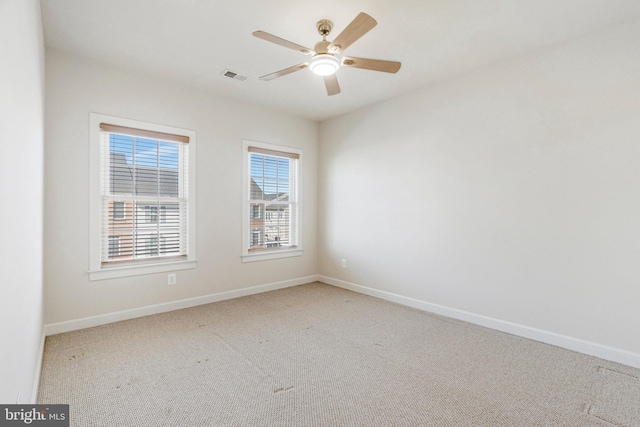 carpeted empty room featuring visible vents, a ceiling fan, and baseboards