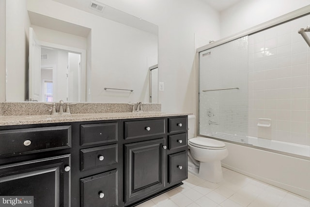 bathroom featuring visible vents, double vanity, a sink, toilet, and combined bath / shower with glass door