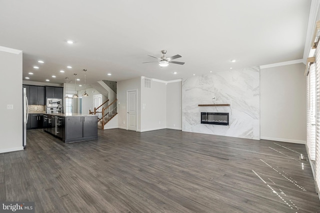 unfurnished living room featuring a ceiling fan, recessed lighting, a fireplace, stairs, and dark wood-type flooring