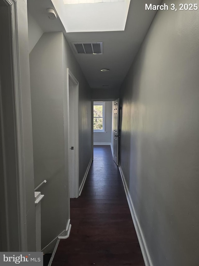 hallway with visible vents, baseboards, and dark wood finished floors