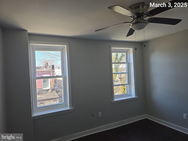 spare room featuring baseboards and dark wood-type flooring