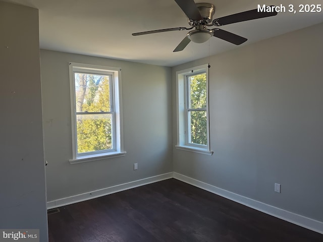 empty room with visible vents, baseboards, ceiling fan, and dark wood-style flooring