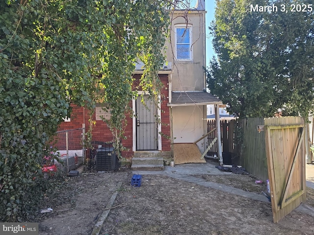 view of front of house with entry steps, cooling unit, fence, and brick siding