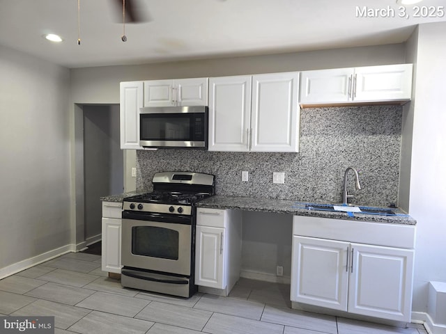 kitchen with decorative backsplash, white cabinets, a sink, and stainless steel appliances