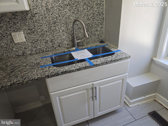 room details with a sink, visible vents, dark stone countertops, and white cabinetry