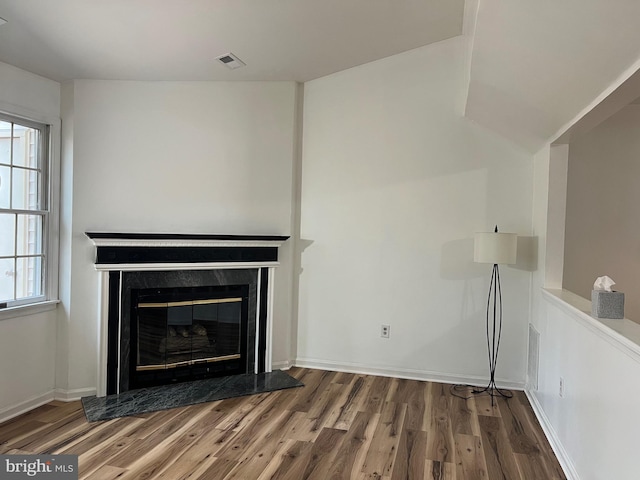 unfurnished living room featuring visible vents, wood finished floors, baseboards, and a premium fireplace