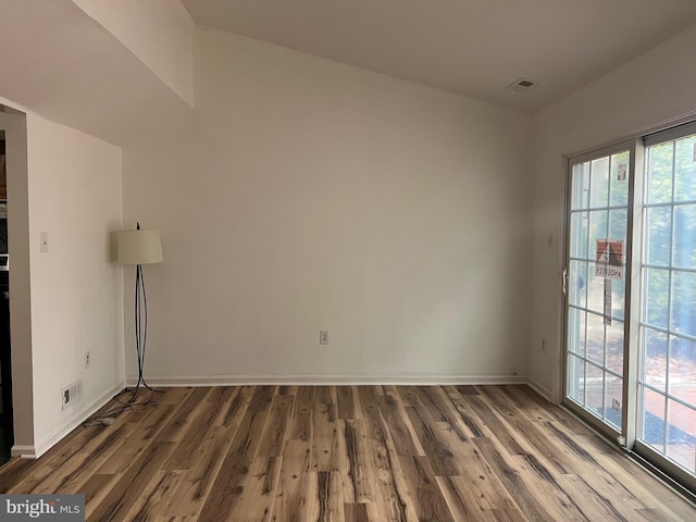 spare room featuring visible vents, baseboards, and wood finished floors