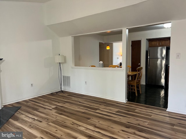 unfurnished living room featuring baseboards, visible vents, and dark wood-style flooring