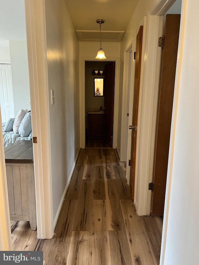 corridor featuring baseboards and light wood-style flooring