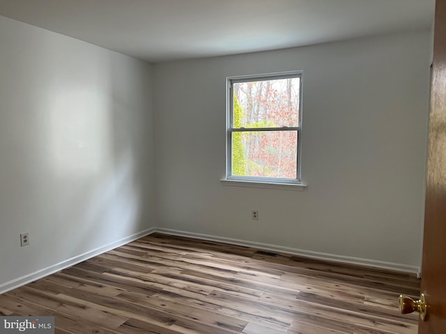 spare room featuring visible vents, baseboards, and wood finished floors