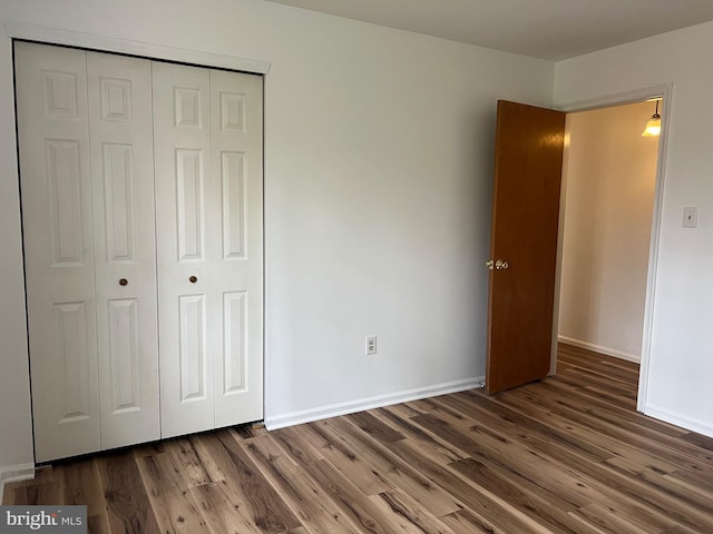 unfurnished bedroom with a closet, baseboards, and wood finished floors