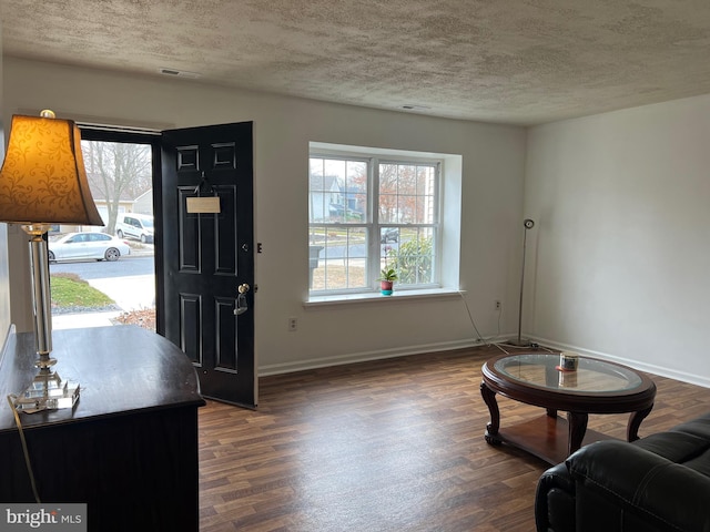 entrance foyer featuring dark wood-style floors, baseboards, and a textured ceiling