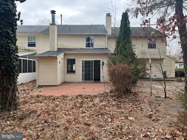 rear view of house with a patio area, a sunroom, and a chimney