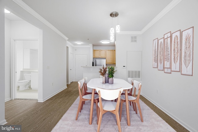 dining area featuring baseboards, wood finished floors, visible vents, and ornamental molding