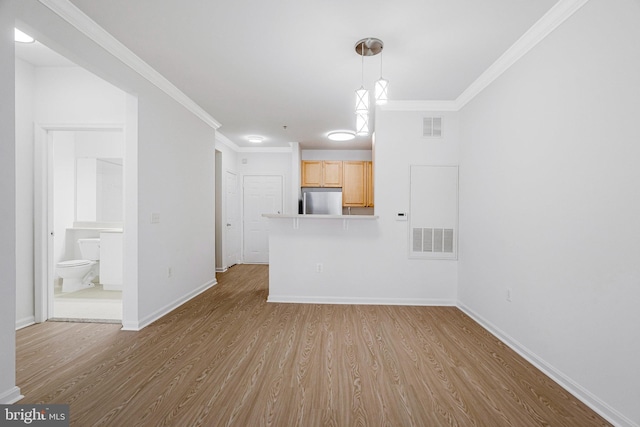 unfurnished living room with visible vents, crown molding, baseboards, and wood finished floors