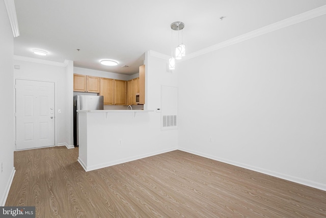 kitchen with baseboards, visible vents, light wood-style flooring, freestanding refrigerator, and ornamental molding