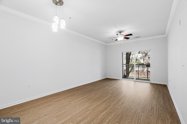 unfurnished room featuring baseboards, wood finished floors, visible vents, and ornamental molding