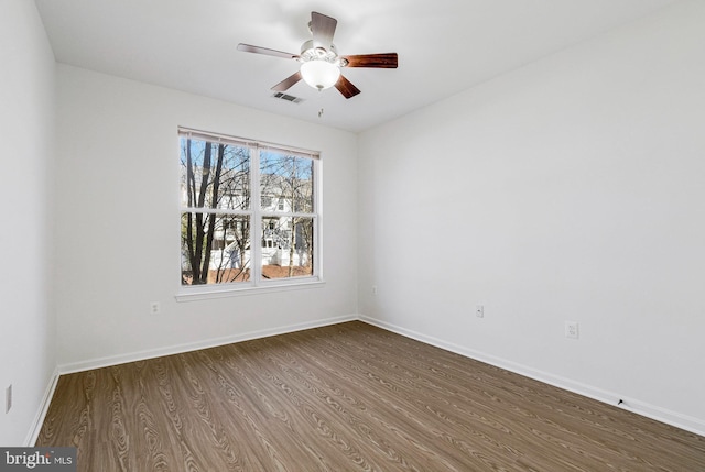 unfurnished room featuring wood finished floors, visible vents, and baseboards