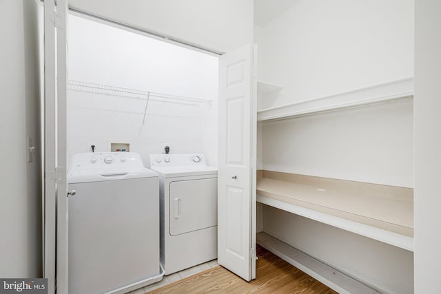 clothes washing area with washer and clothes dryer, laundry area, and light wood-style floors