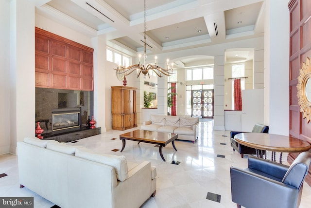 living area with coffered ceiling, a fireplace, a high ceiling, and an inviting chandelier