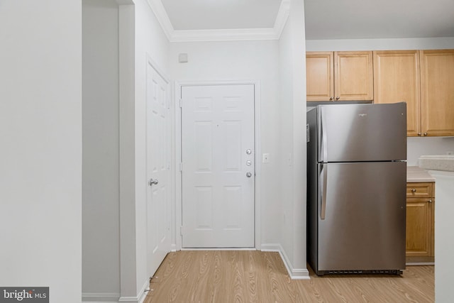 kitchen with light wood-style flooring, light brown cabinets, ornamental molding, freestanding refrigerator, and light countertops