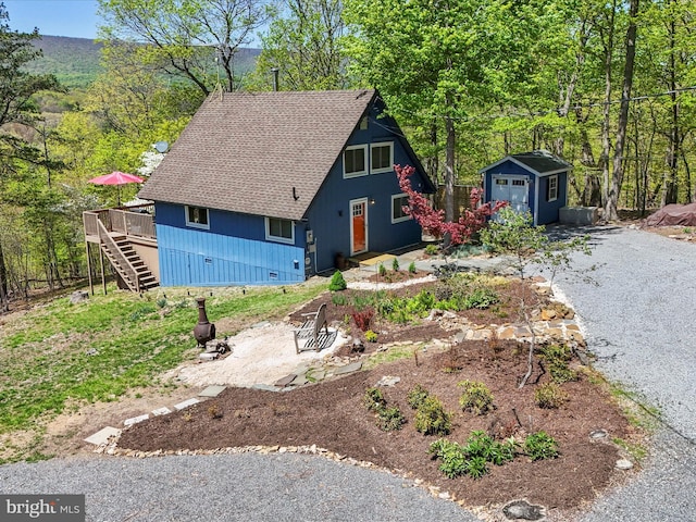 777 Timber Ln, Berkeley Springs, WV 25411 - a-frame style home featuring an outbuilding, a wooden deck, a storage unit, a shingled roof, and stairs