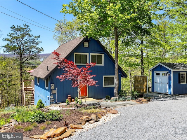 777 Timber Ln, Berkeley Springs, WV 25411 - view of front of property featuring a storage unit, stairs, a shingled roof, a wooden deck, and an outbuilding