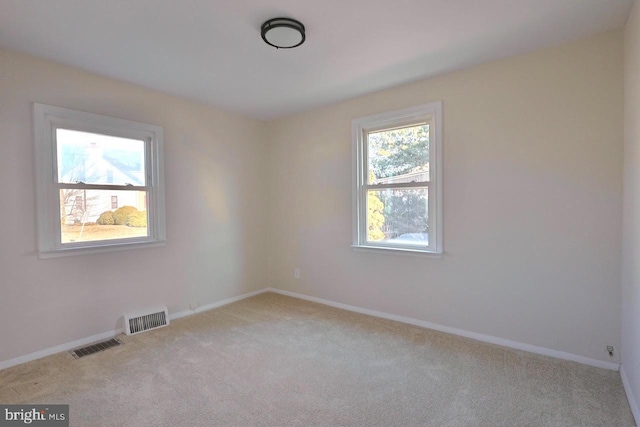 spare room featuring a wealth of natural light, visible vents, and carpet flooring