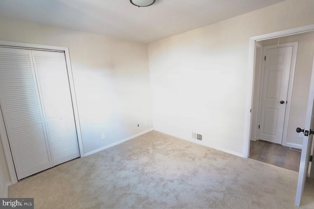 unfurnished bedroom with visible vents, baseboards, carpet, attic access, and a closet